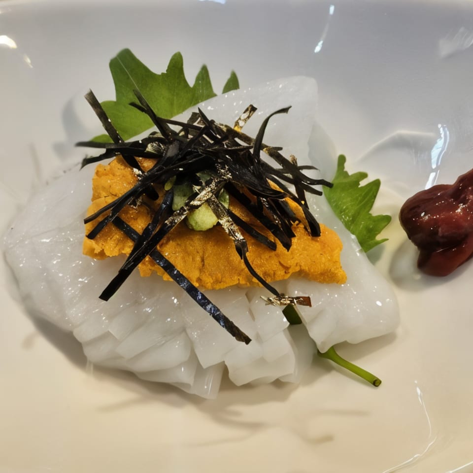 Sushi Bei's squid sashimi topped with bright orange uni, dark seaweed, and green garnish.